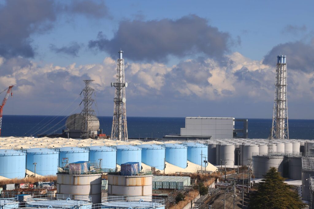 構内入り口近くの大型休憩所７階から見た３号機（左奥）と４号機（右奥）。手前に多核種除去設備などを通しトリチウム以外の62物質を低減させたＡＬＰＳ処理水などを収めたタンクが並ぶ。