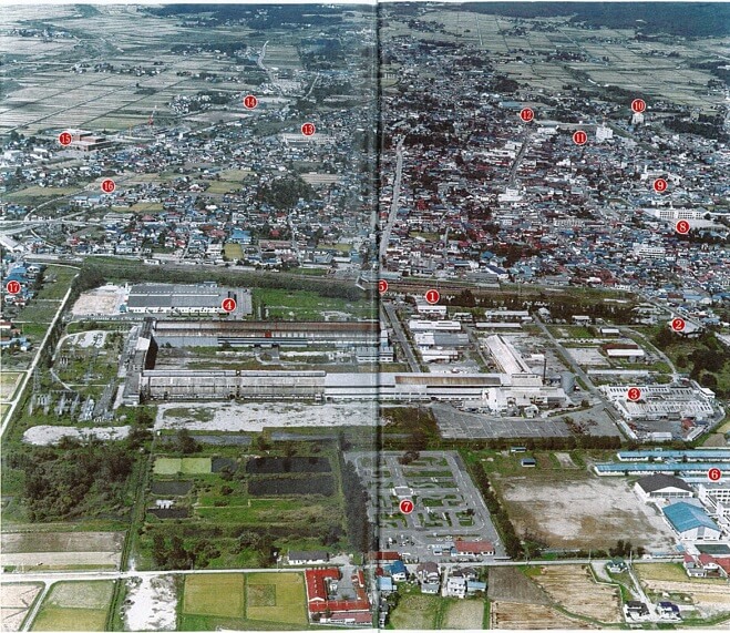 喜多方事業所を南側から撮った１９９５年の航空写真（出典：喜多方昭寿会「昭和電工喜多方工場六十年の歩み」）。中央①が正門。北側を東西にＪＲ磐越西線が走り、市街地が広がる。駅北側の湧水は戦前から枯れ始めた。写真左端の⑰は太郎丸行政区。
