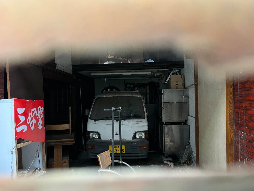 建物の中を覗いたら看板と車がそのまま置かれていた