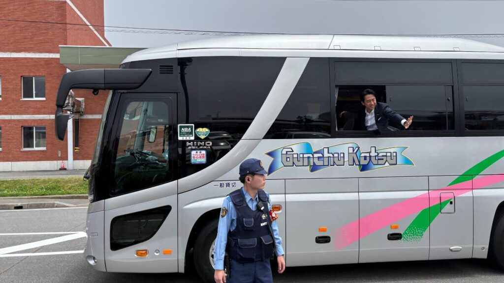 バスから身を乗り出して手を振る小泉進次郎農水相